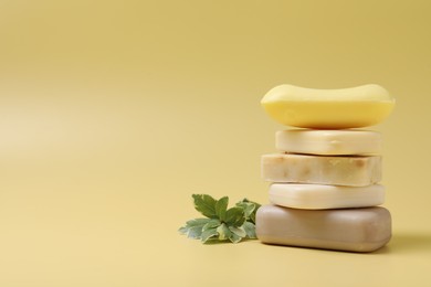 Many different soap bars stacked on yellow background, space for text