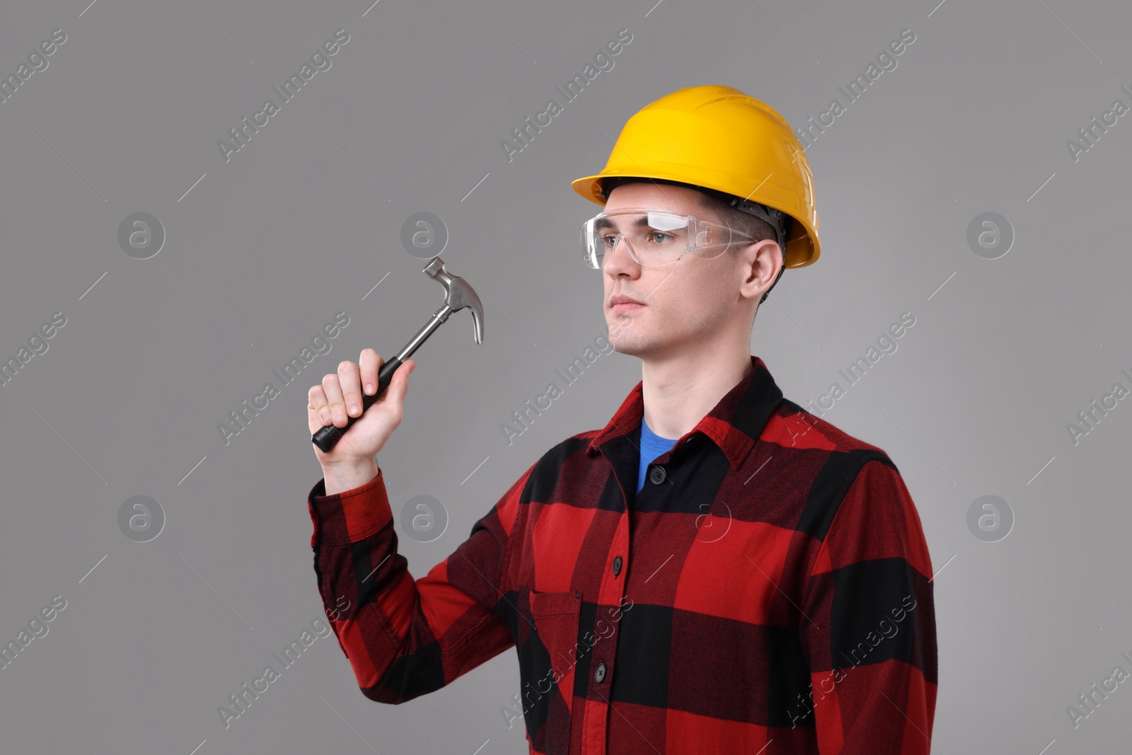 Photo of Professional repairman holding hammer on light grey background