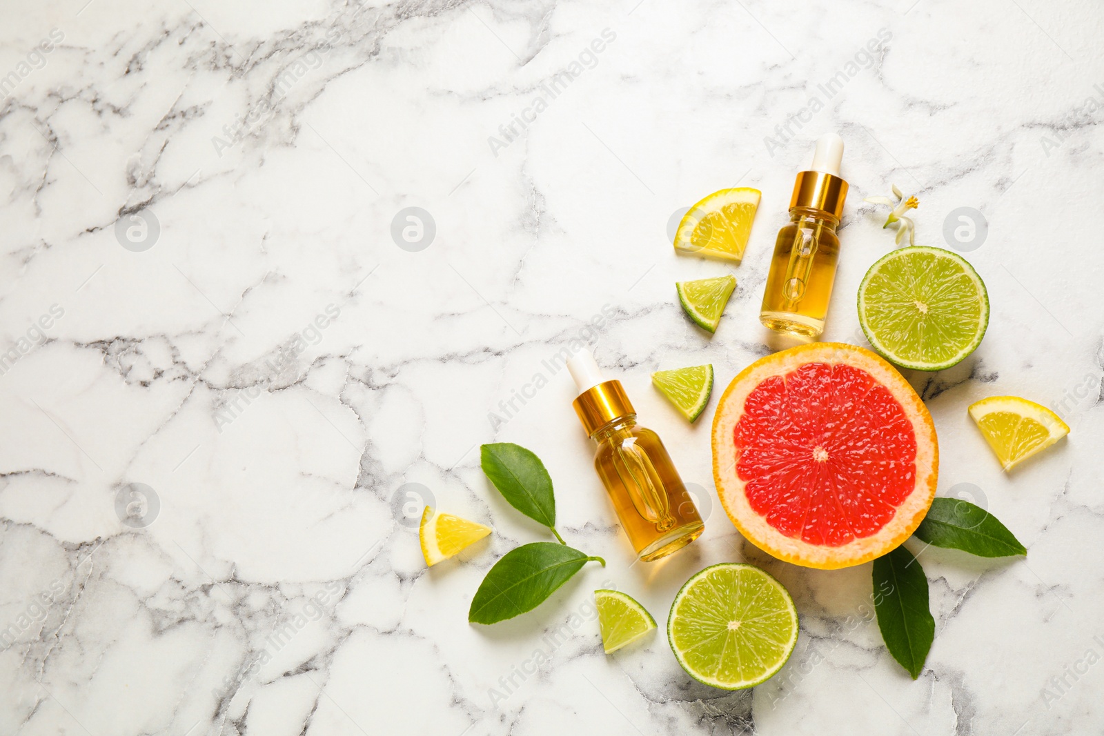 Photo of Flat lay composition with bottles of citrus essential oil on white marble background. Space for text