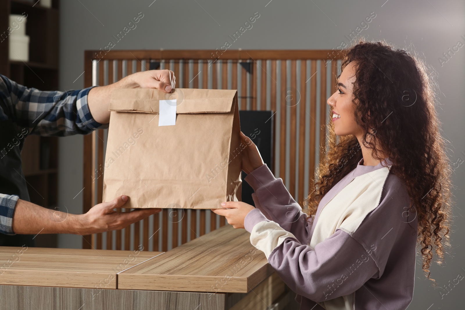 Photo of Worker giving paper bag to customer in cafe