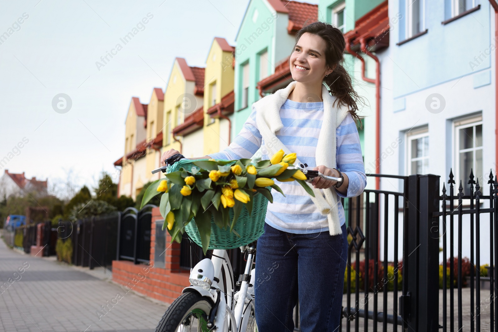 Photo of Beautiful woman with bicycle and bouquet of yellow tulips on city street