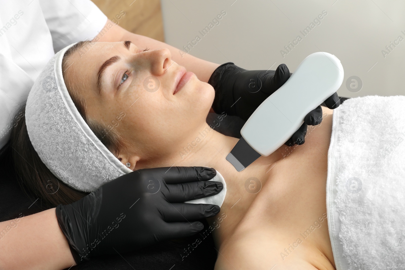 Photo of Cosmetologist using ultrasonic scrubber, closeup. Client having cleansing procedure in clinic