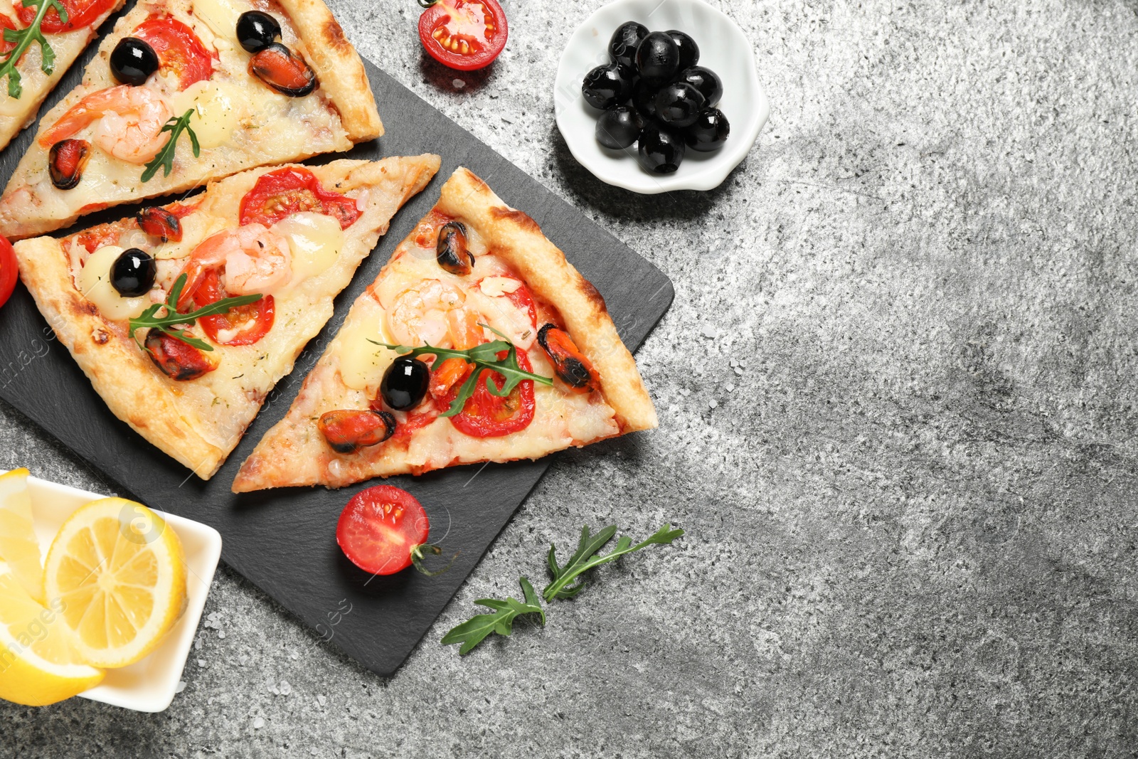 Photo of Tasty pizza with seafood and ingredients on grey table, flat lay. Space for text