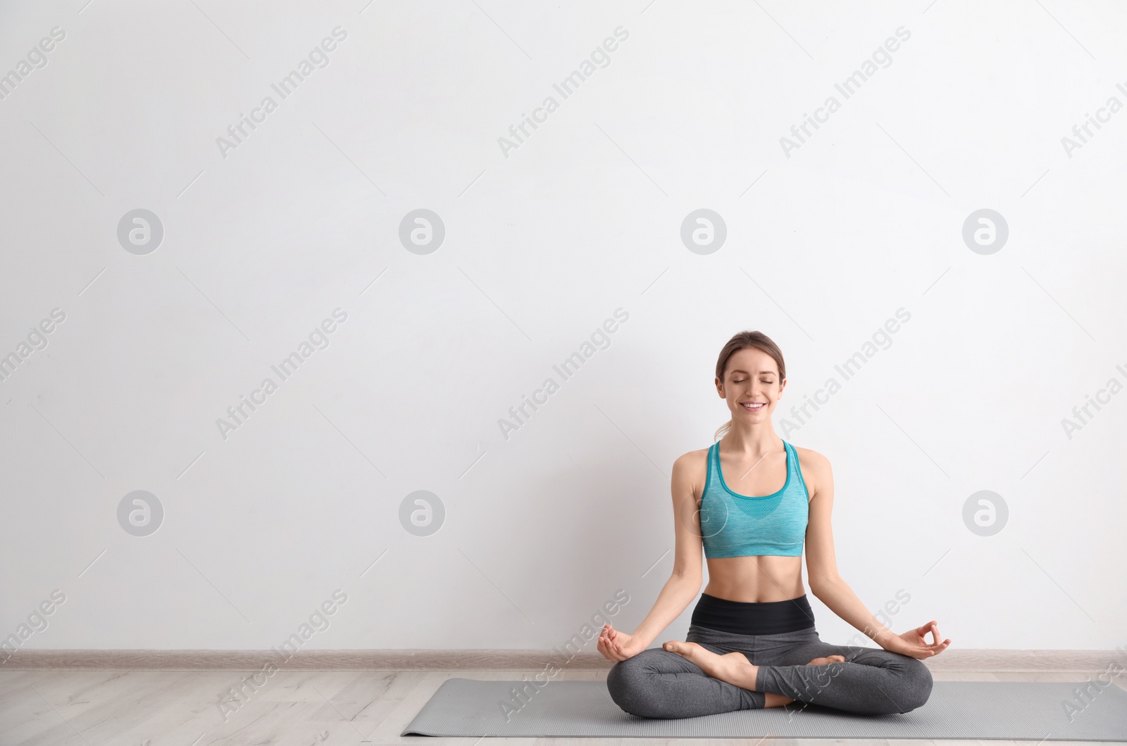 Photo of Young woman meditating near light wall, space for text. Zen concept