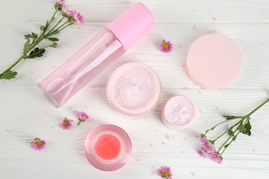 Photo of Homemade cosmetic products and beautiful flowers on white wooden table, flat lay
