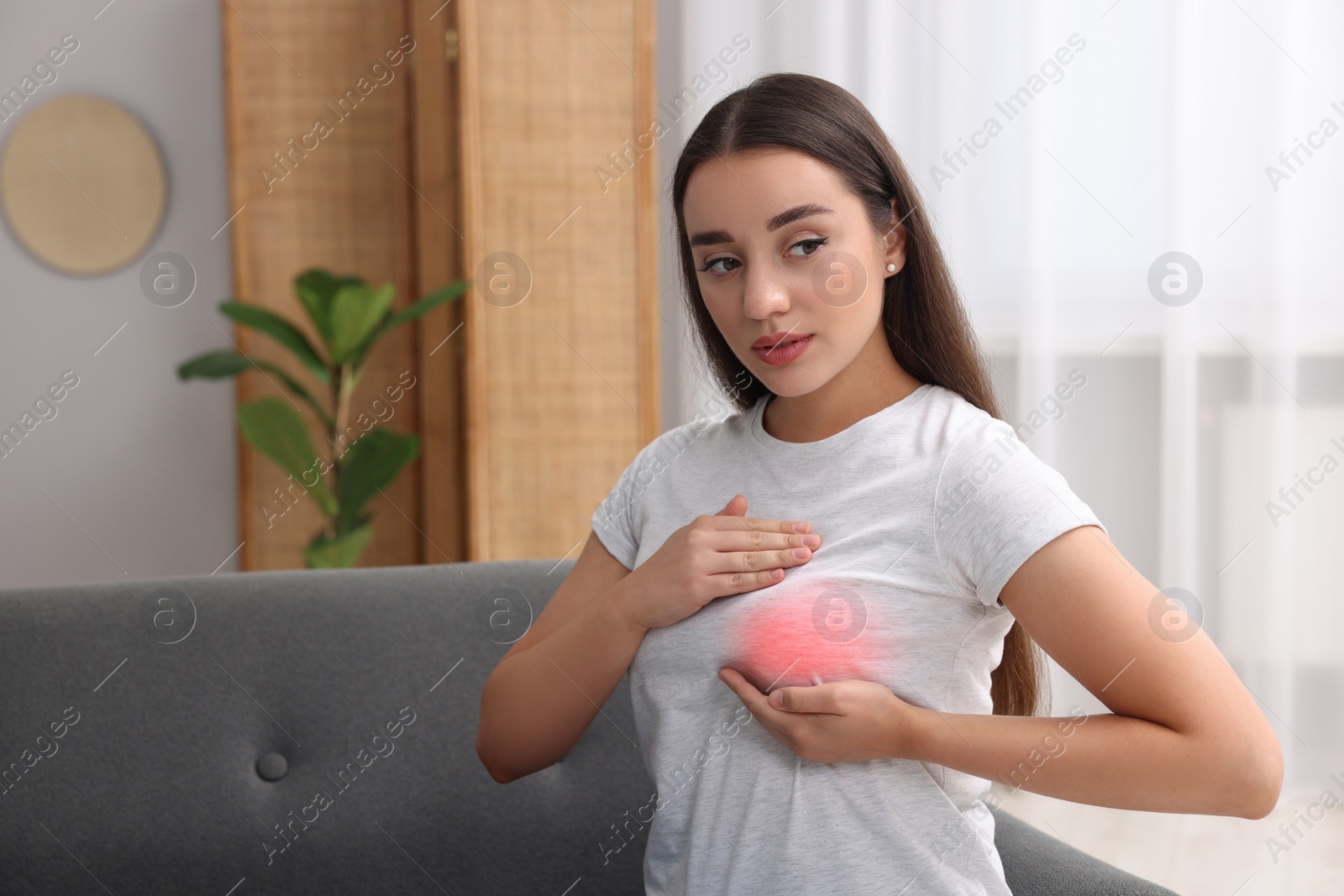 Image of Beautiful young woman doing breast self-examination at home, space for text