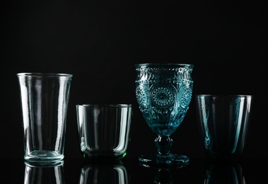 Photo of Set of different colorful empty glasses on black background