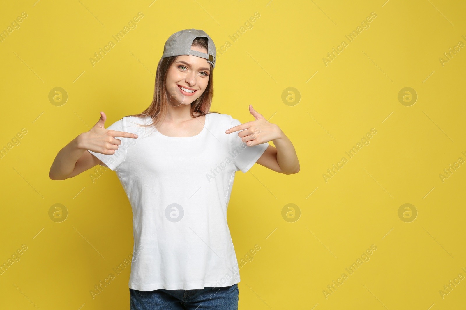 Photo of Young woman wearing blank t-shirt on yellow background. Mockup for design