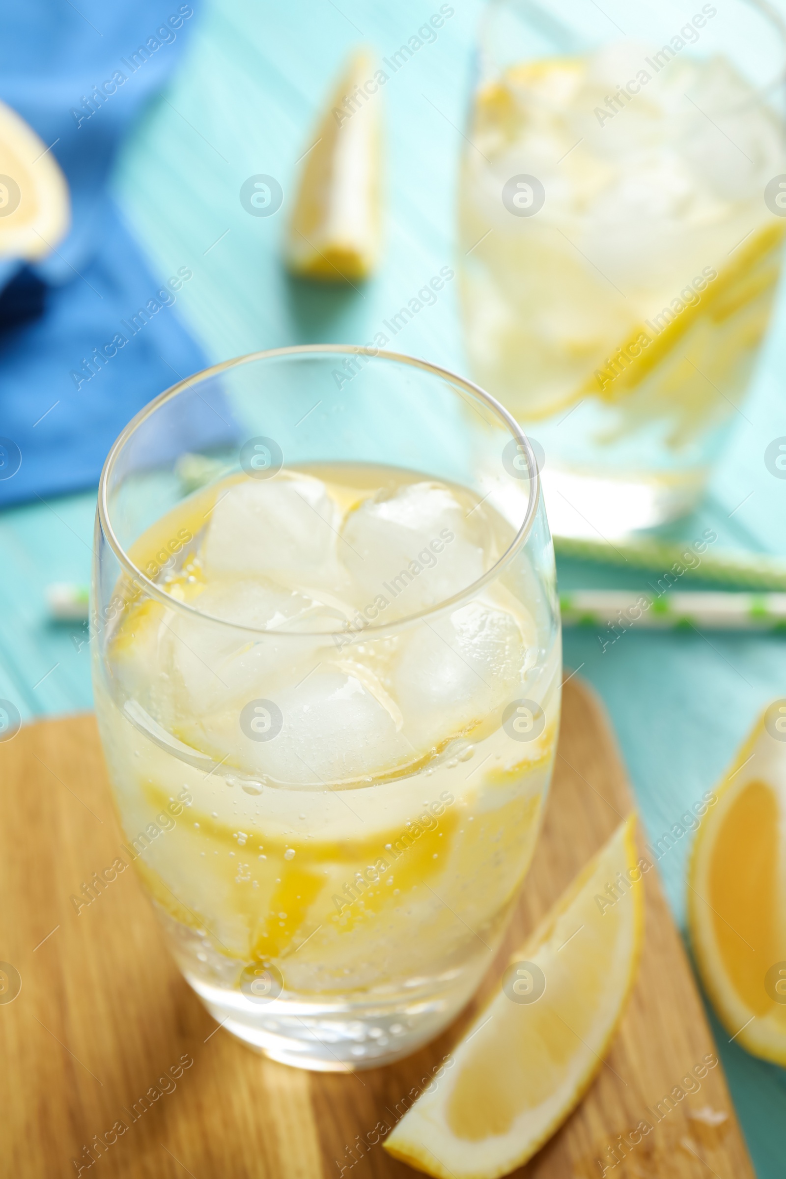 Photo of Soda water with lemon slices and ice cubes on light blue wooden table