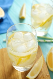 Soda water with lemon slices and ice cubes on light blue wooden table