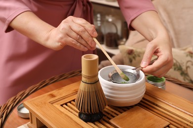 Photo of Master preparing matcha drink at wooden table, closeup. Tea ceremony