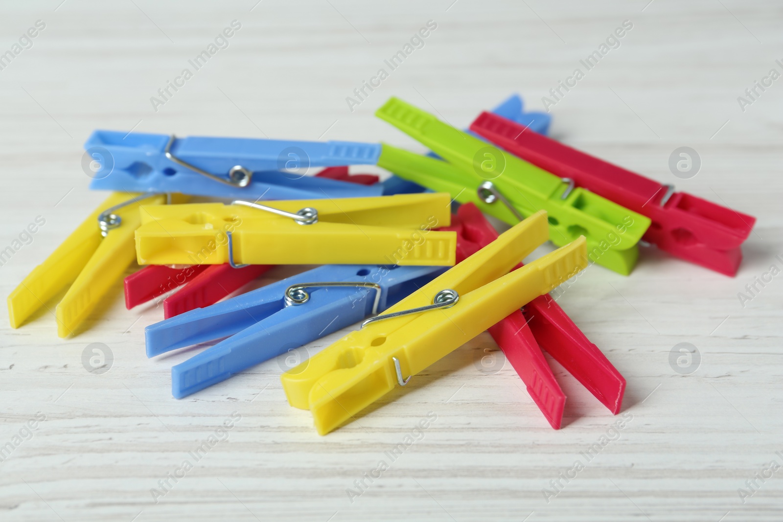 Photo of Colorful plastic clothespins on white wooden table, closeup