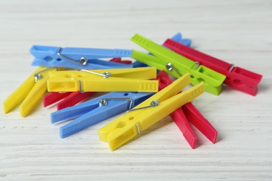 Colorful plastic clothespins on white wooden table, closeup