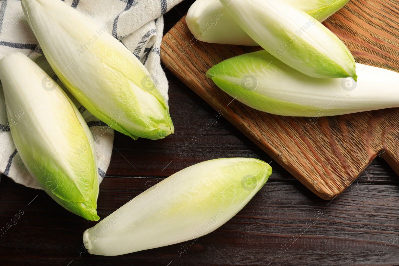 Photo of Raw ripe chicories on wooden table, top view