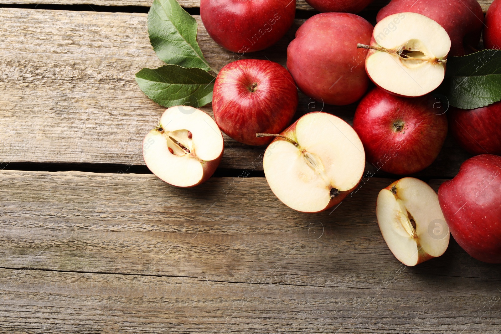 Photo of Fresh red apples and leaves on wooden table, flat lay. Space for text