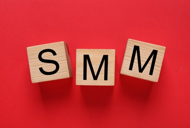Photo of Cubes with abbreviation SMM (Social media marketing) on red background, flat lay