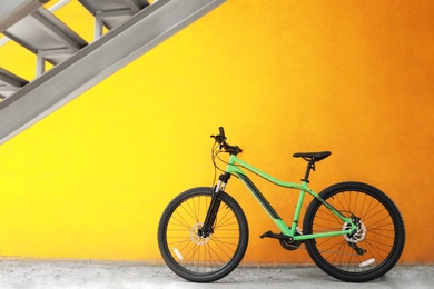 Photo of New modern color bicycle near yellow wall outdoors