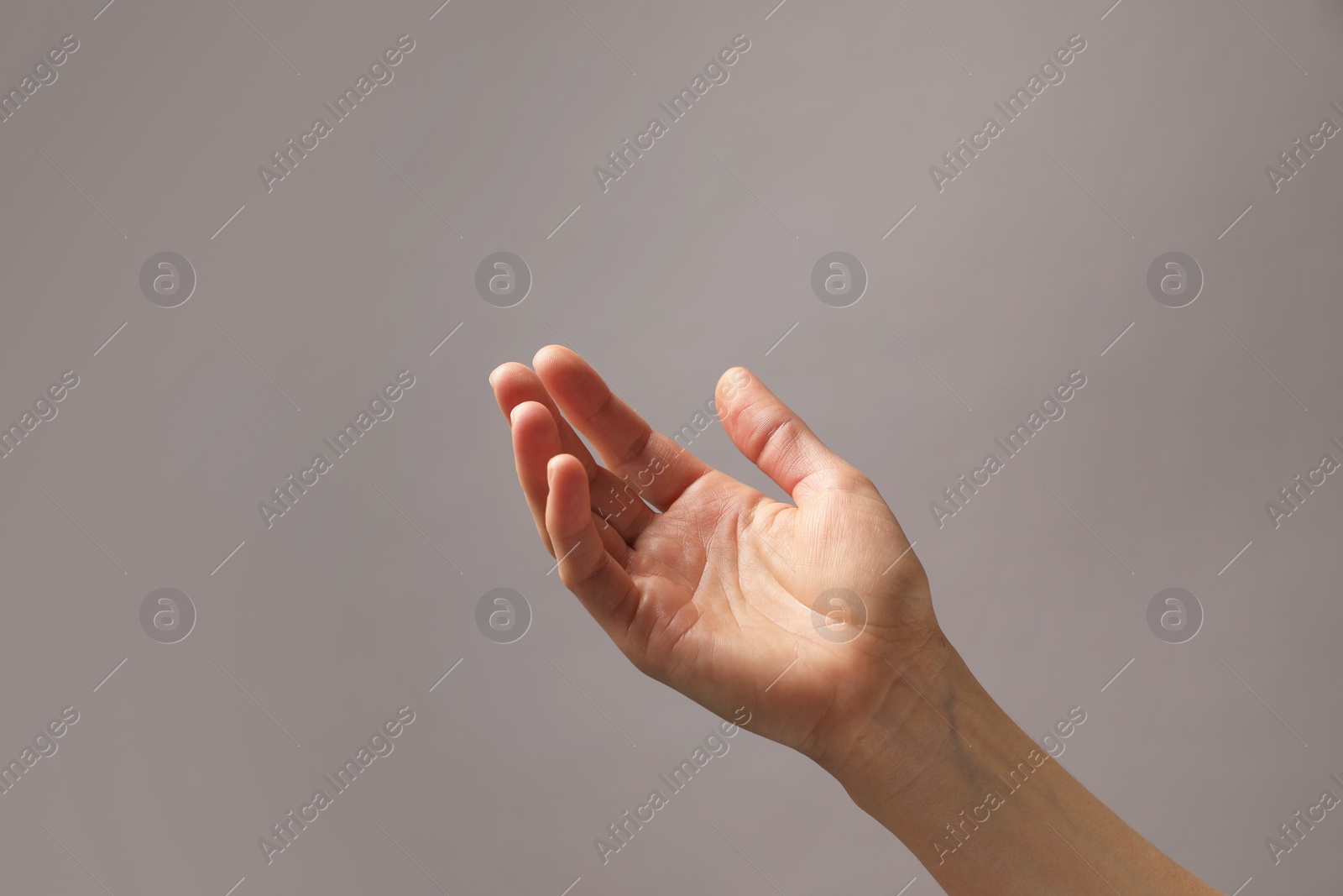 Photo of Woman holding something in hand on grey background, closeup