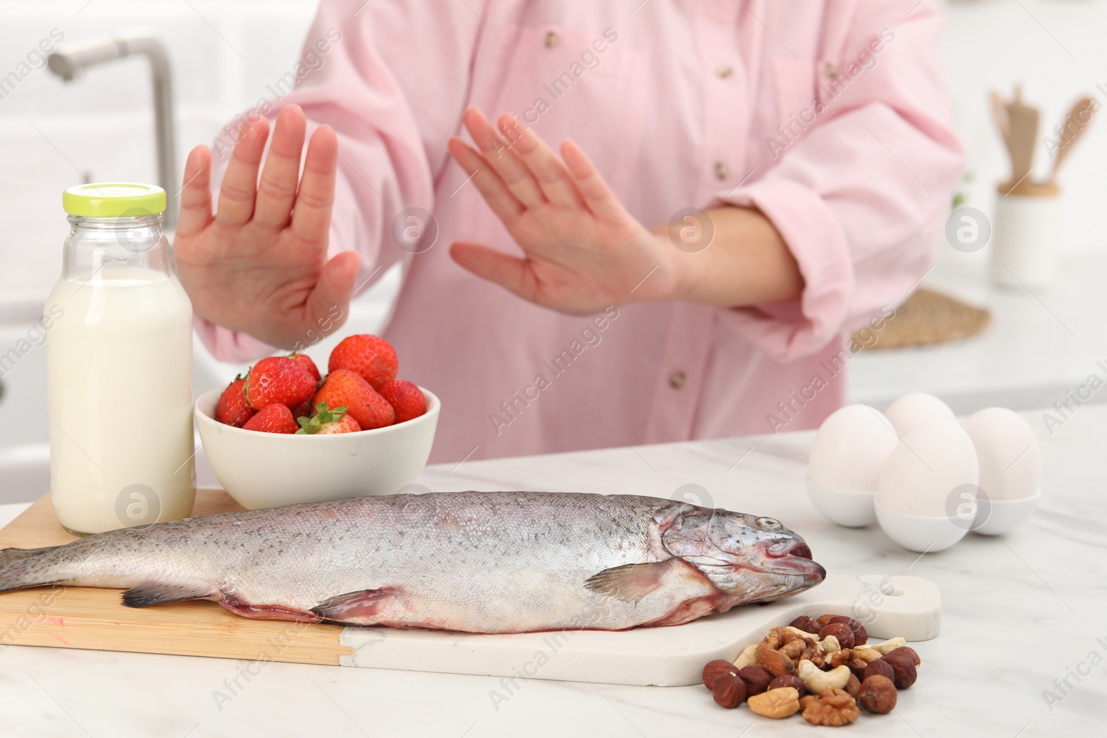 Photo of Woman suffering from food allergies refusing eat different fresh products at light table indoors, closeup