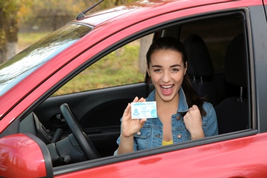 Photo of Happy woman showing driving license from new car