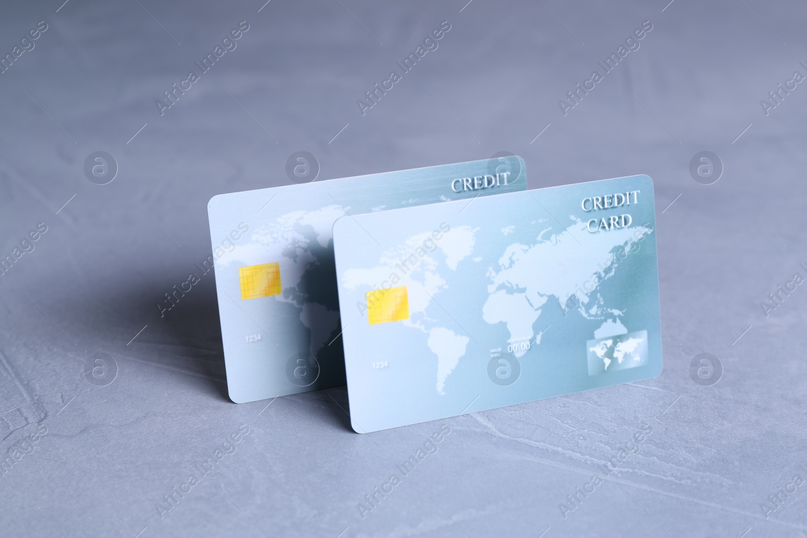 Photo of Two credit cards on grey textured table, closeup