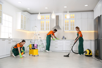 Photo of Team of professional janitors cleaning modern kitchen