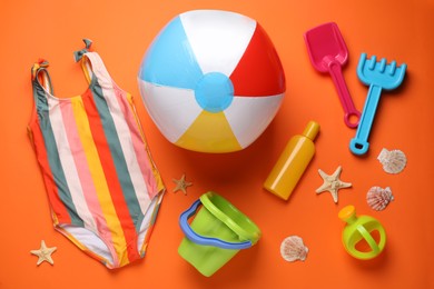 Photo of Flat lay composition with colorful beach ball and sand toys on orange background