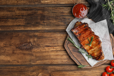 Photo of Tasty grilled ribs on wooden table, flat lay. Space for text
