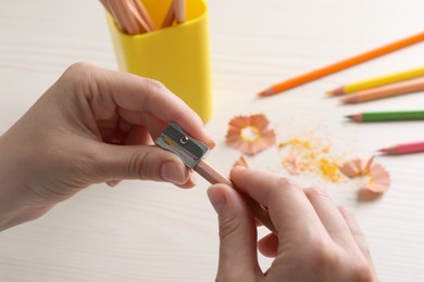 Woman sharpening pencil at wooden table, closeup