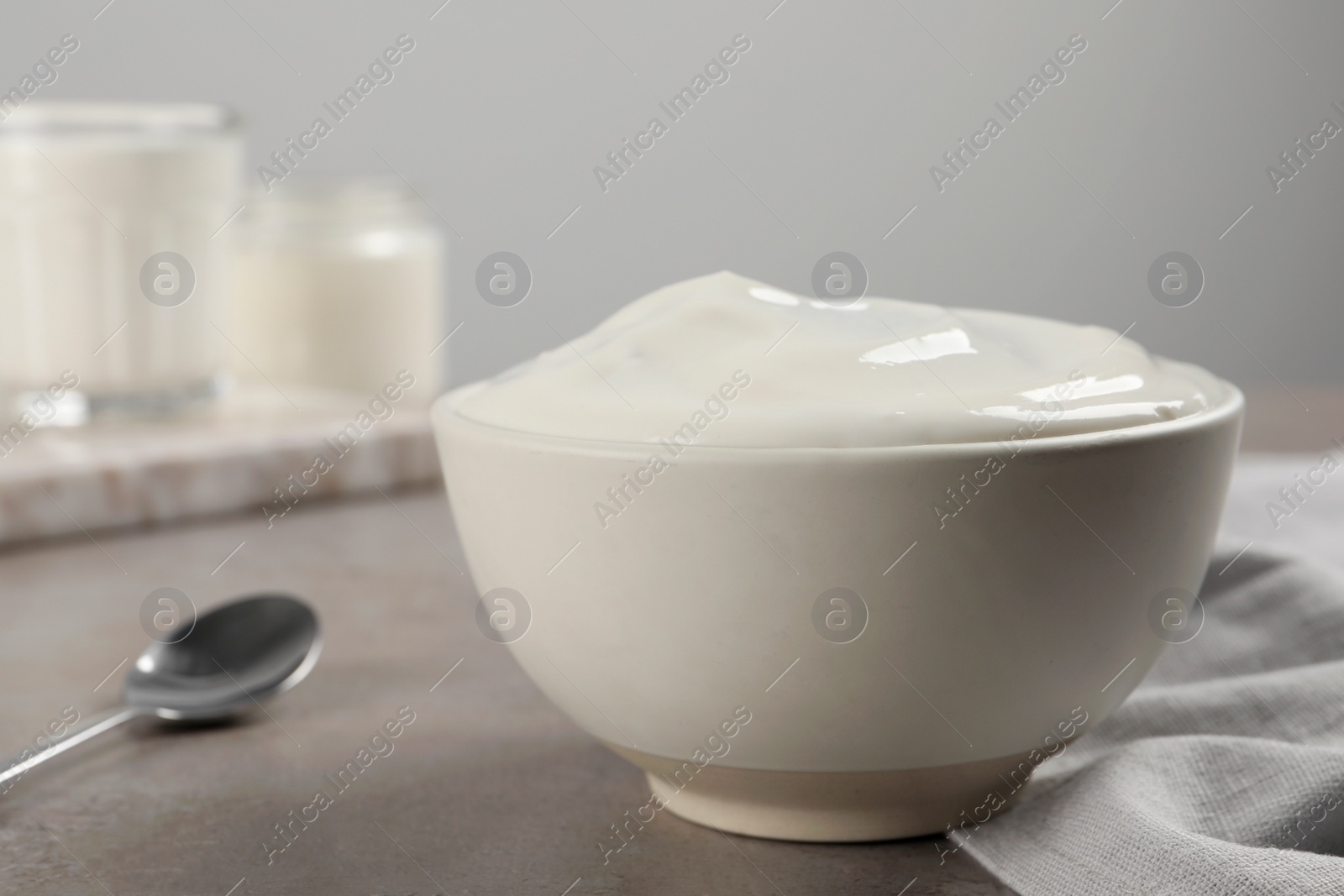 Photo of Bowl with delicious organic yogurt on grey table, closeup