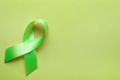 Photo of World Mental Health Day. Green ribbon on color background, top view with space for text