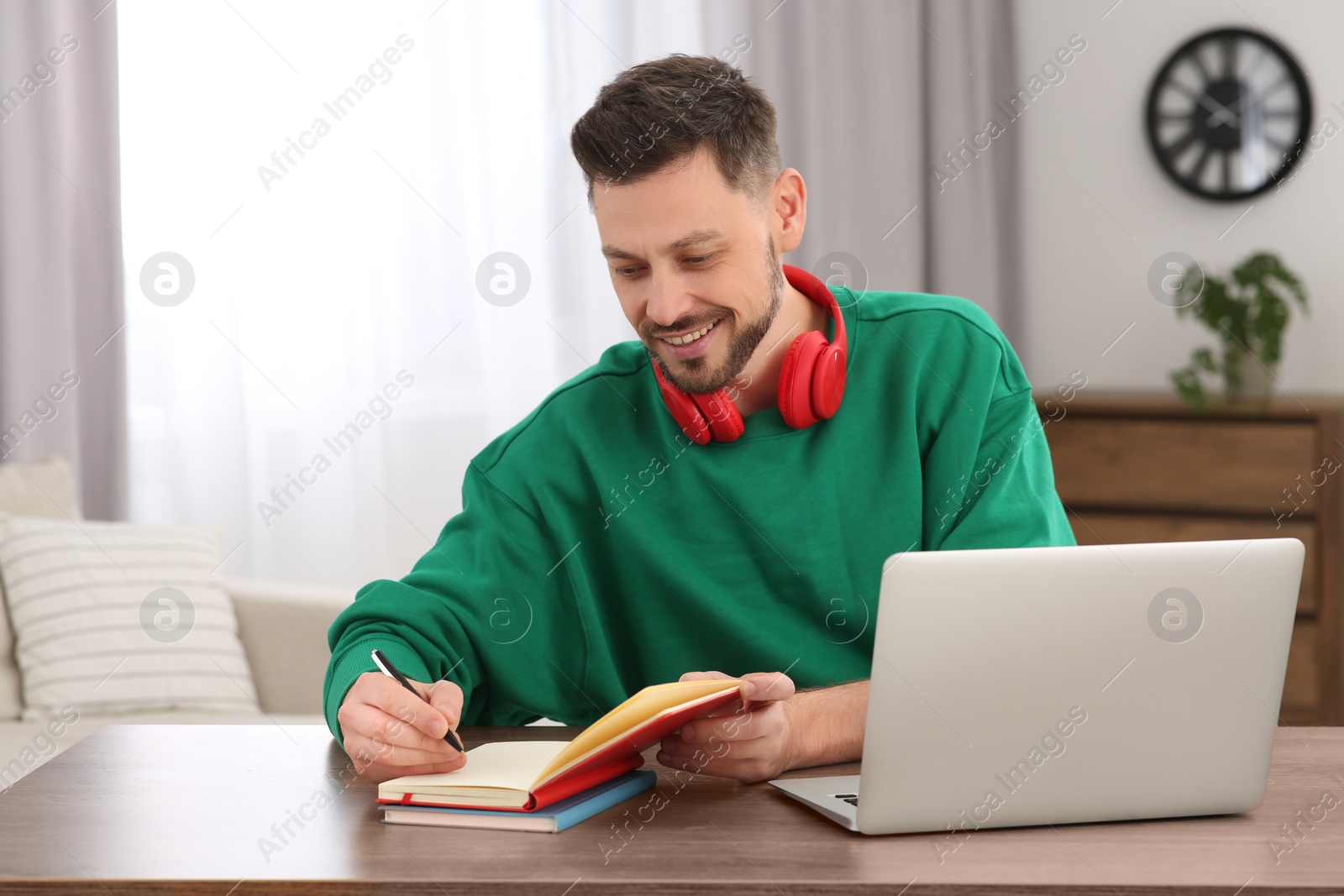 Photo of Online translation course. Man writing near laptop at home