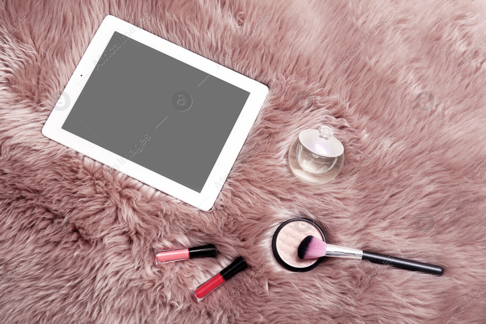 Photo of Flat lay composition with tablet and makeup products for woman on fur