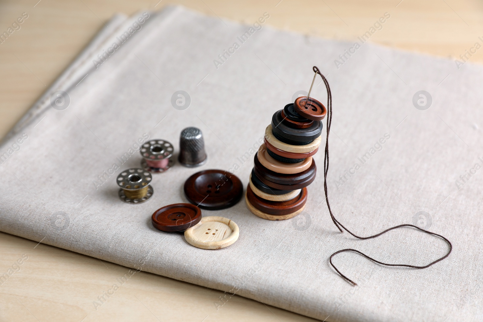 Photo of Set of sewing supplies and accessories with fabric on wooden table