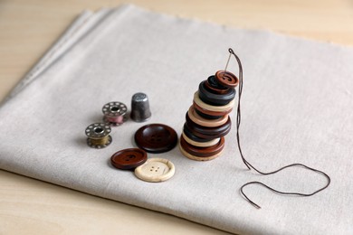 Photo of Set of sewing supplies and accessories with fabric on wooden table