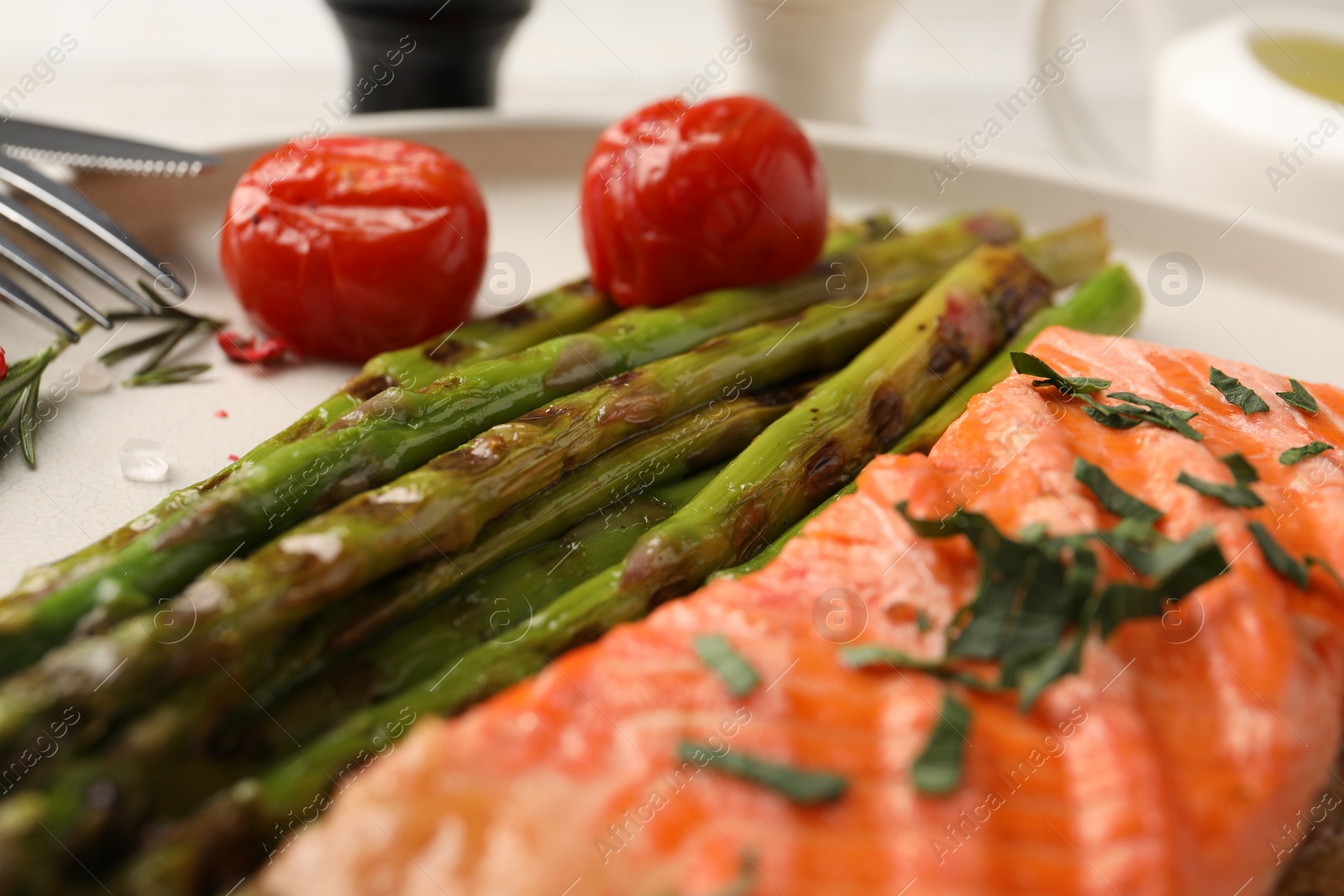 Photo of Tasty grilled salmon with tomatoes, asparagus and spices on table, closeup