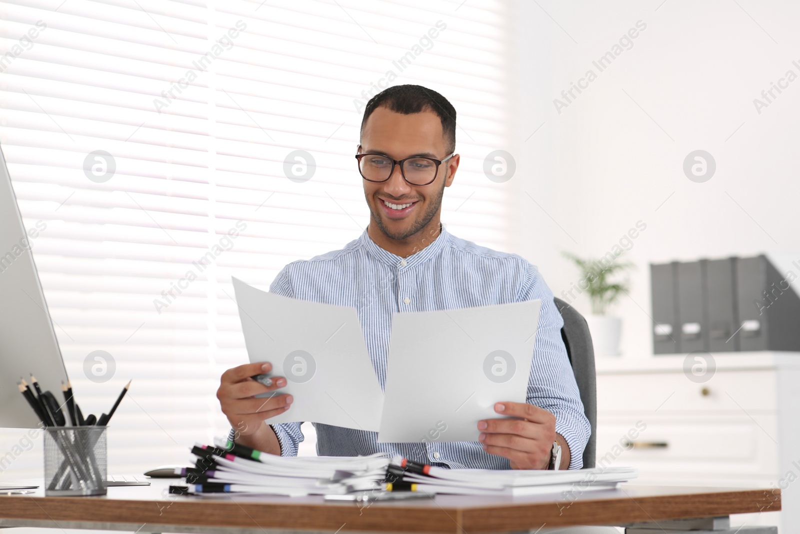 Photo of Happy businessman working with documents at wooden table in office