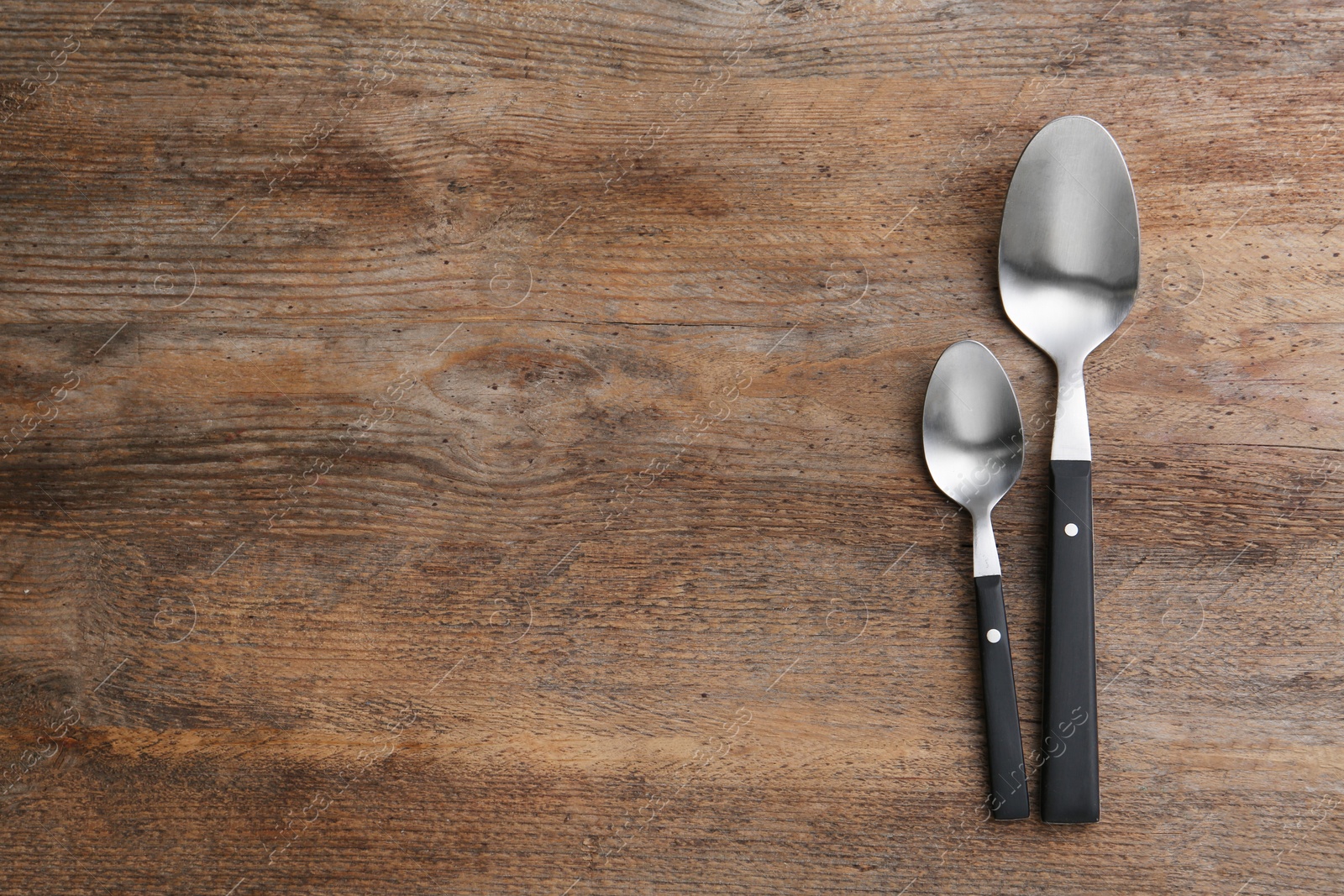 Photo of Clean empty table spoons on wooden background, top view. Space for text