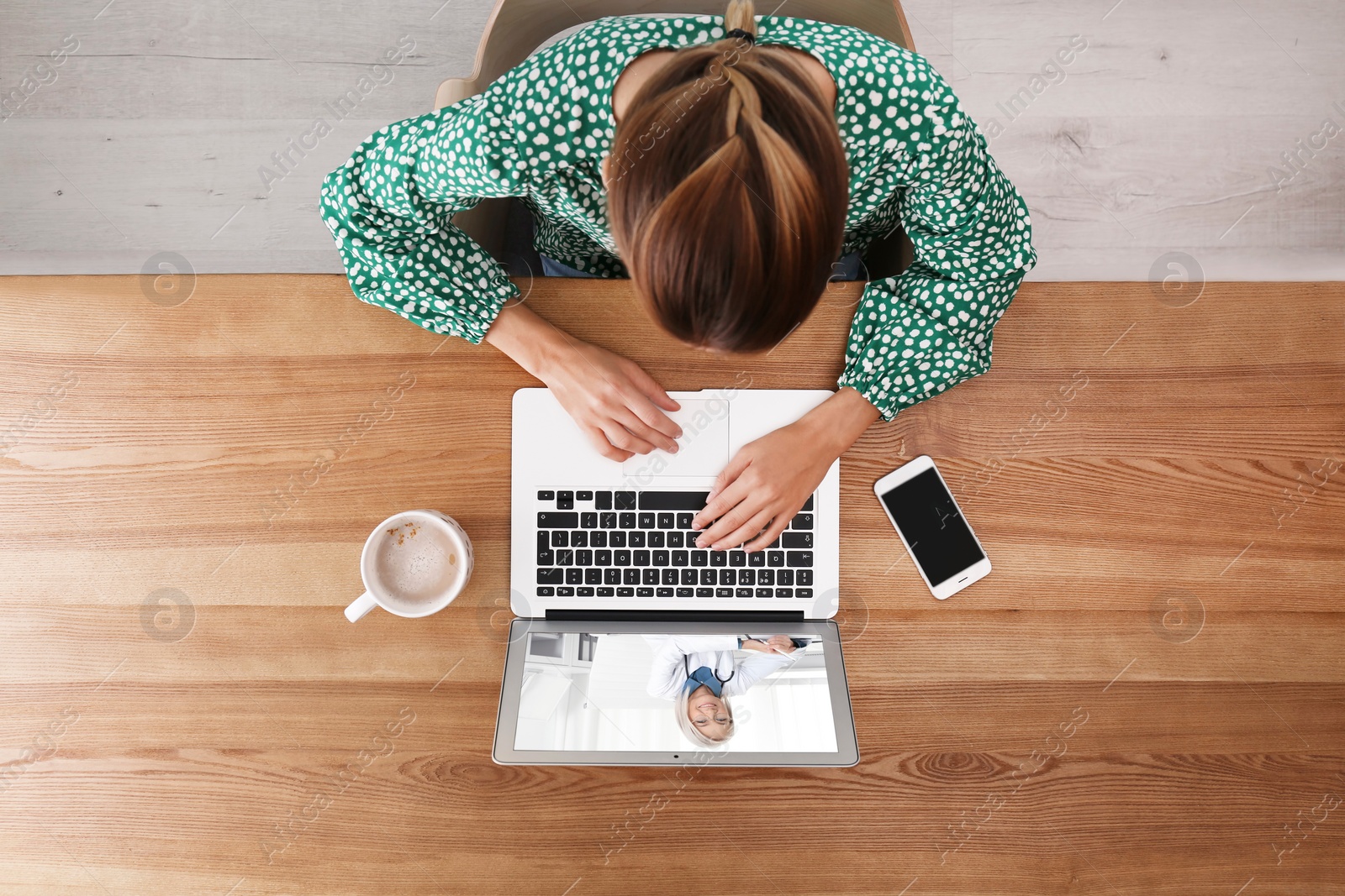 Image of Woman using laptop for online consultation with mature female doctor, top view 