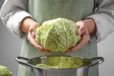 Photo of Woman holding fresh savoy cabbage above colander, closeup