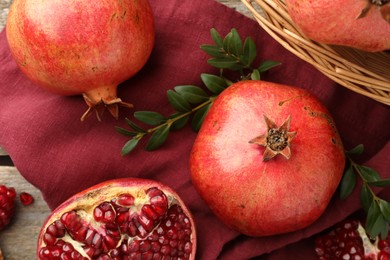 Photo of Fresh pomegranates and green leaves on table, top view