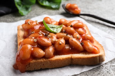 Toast with delicious canned beans on grey table, closeup