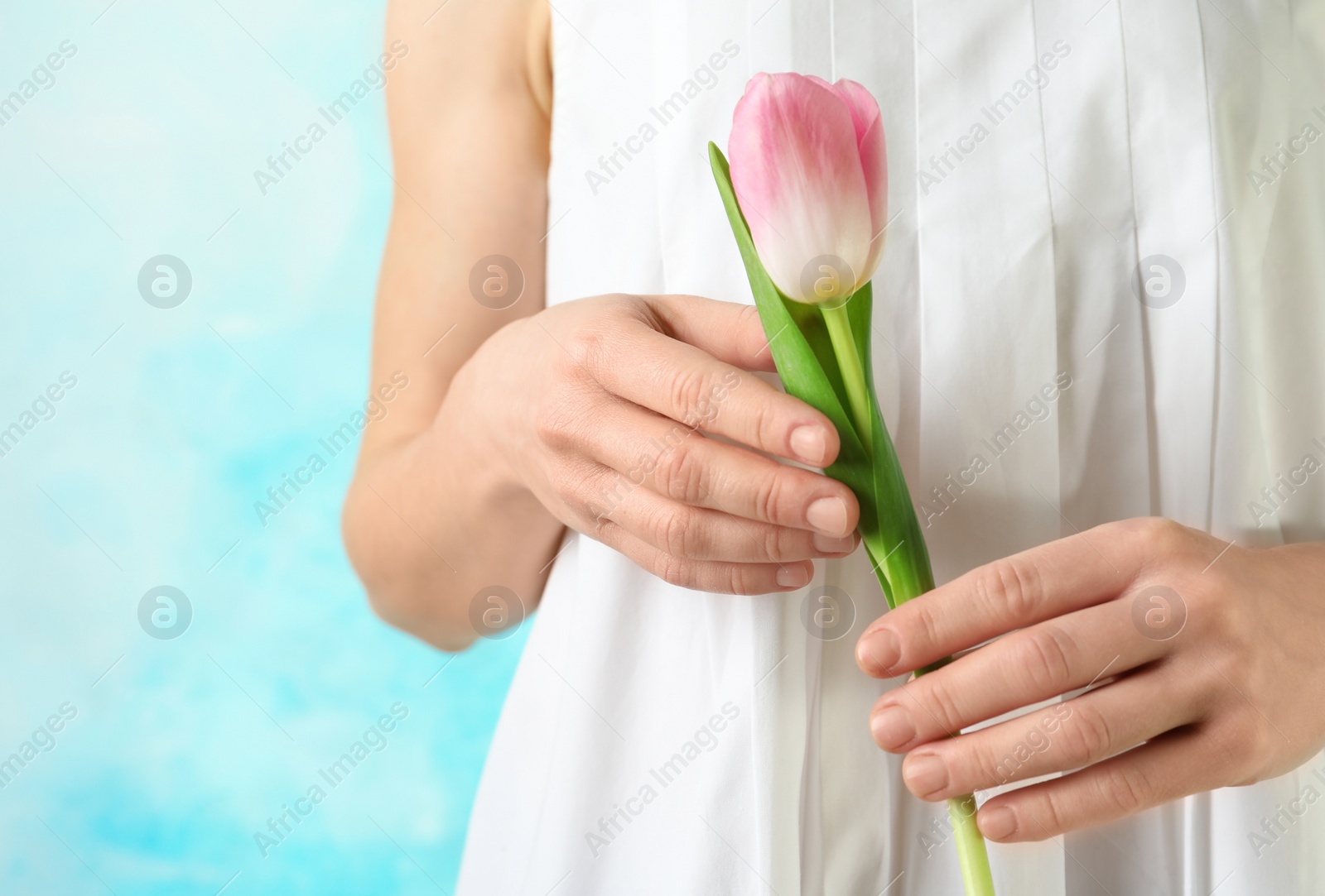 Photo of Girl holding beautiful spring tulip on color background, closeup. International Women's Day