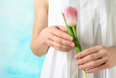 Girl holding beautiful spring tulip on color background, closeup. International Women's Day