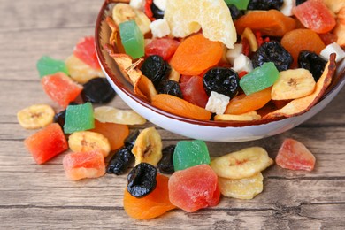 Photo of Bowl and different tasty dried fruits on wooden table, closeup