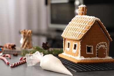 Photo of Beautiful gingerbread house decorated with icing on grey table