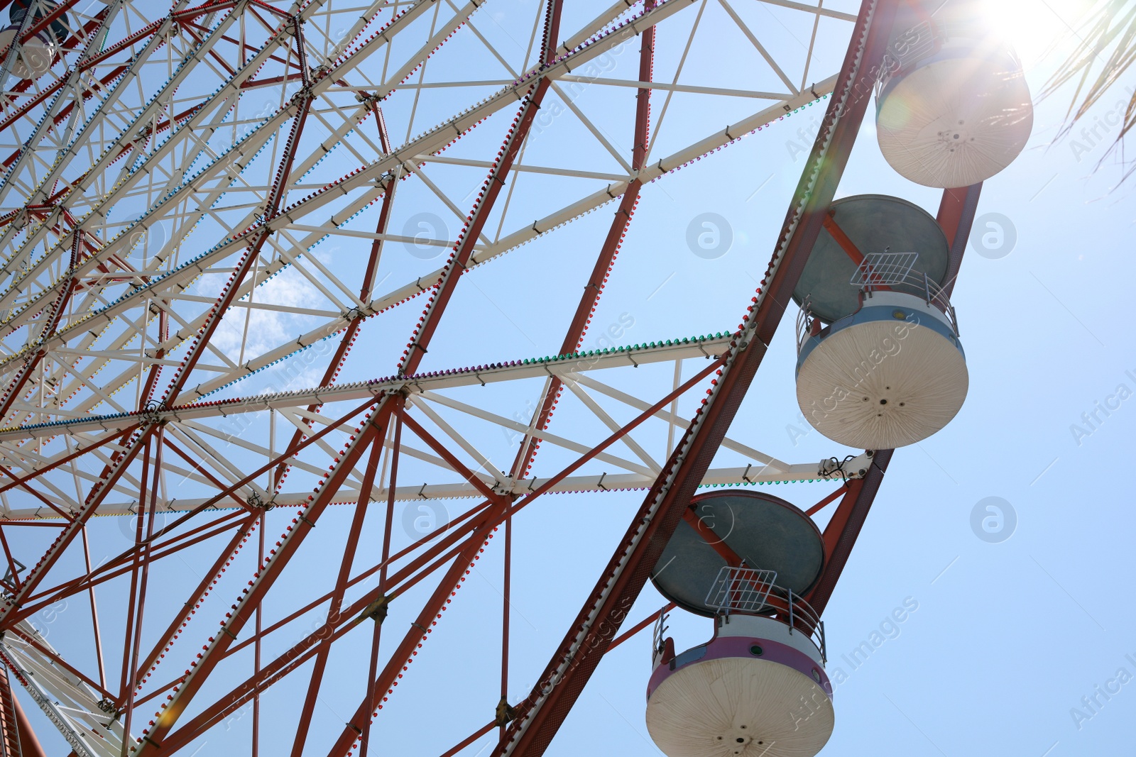 Photo of Beautiful Ferris wheel against blue sky on sunny day, low angle view