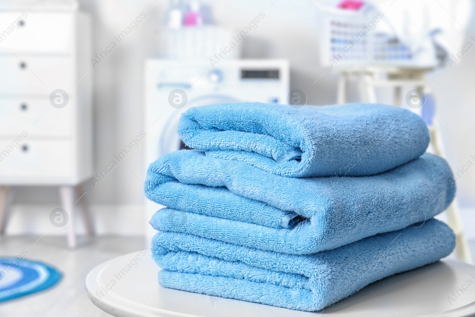 Photo of Stack of clean towels on table in laundry room. Space for text