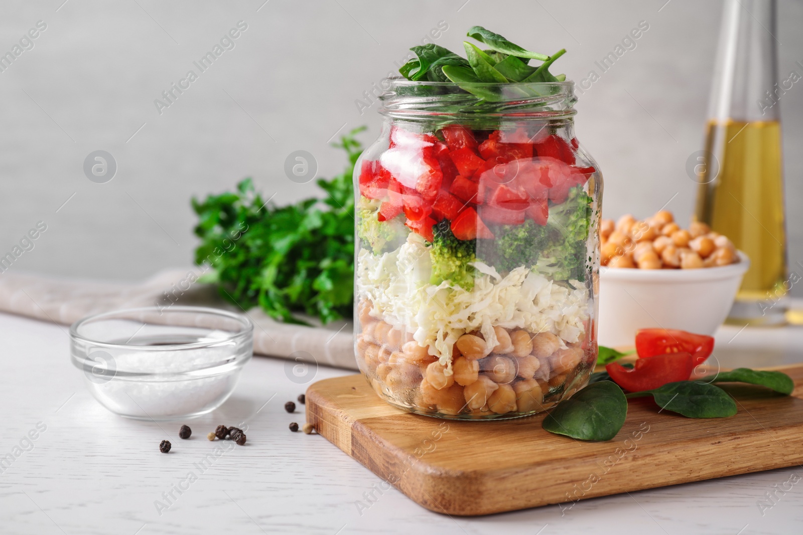 Photo of Healthy salad in glass jar on white table