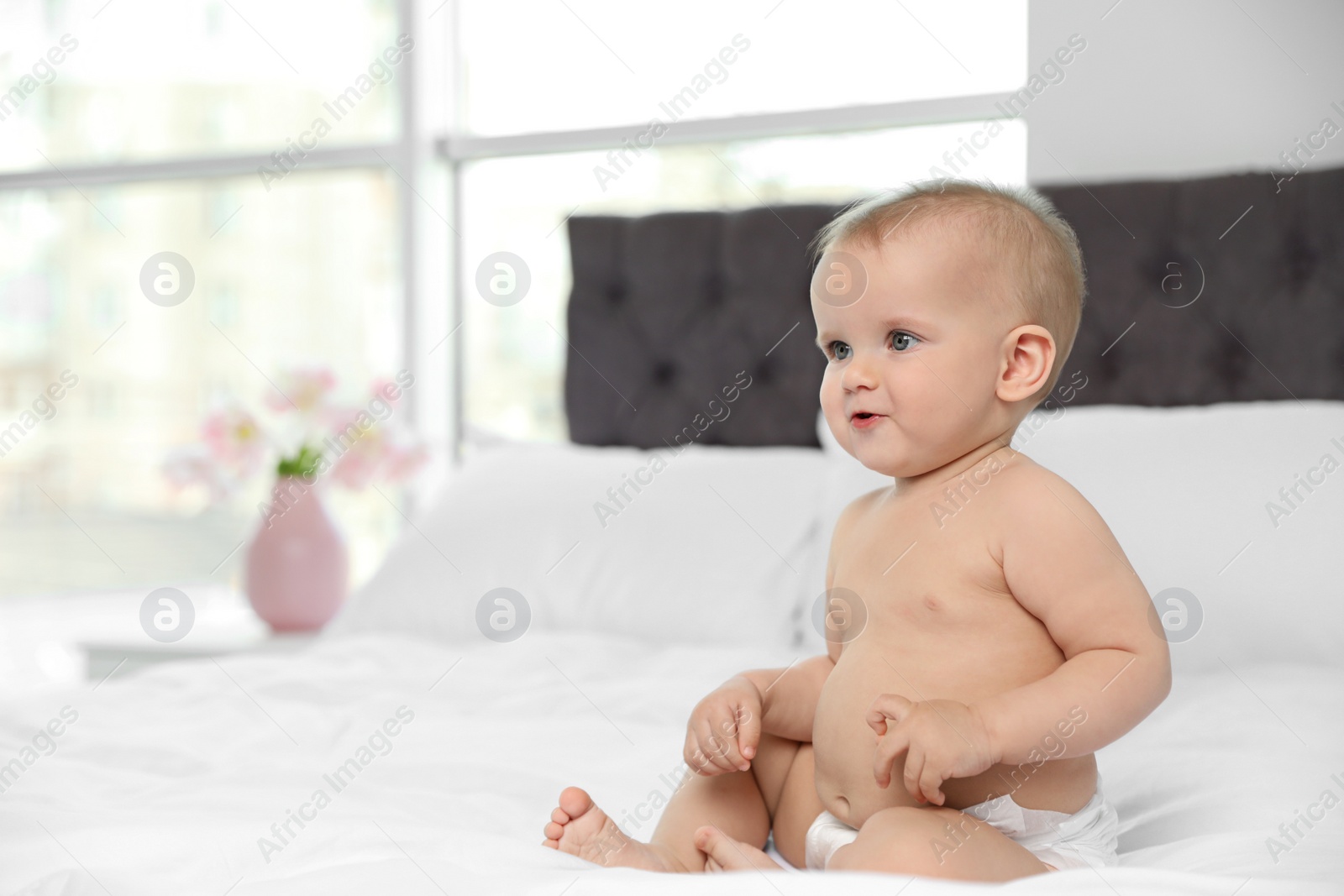 Photo of Cute baby in diaper on bed at home. Space for text